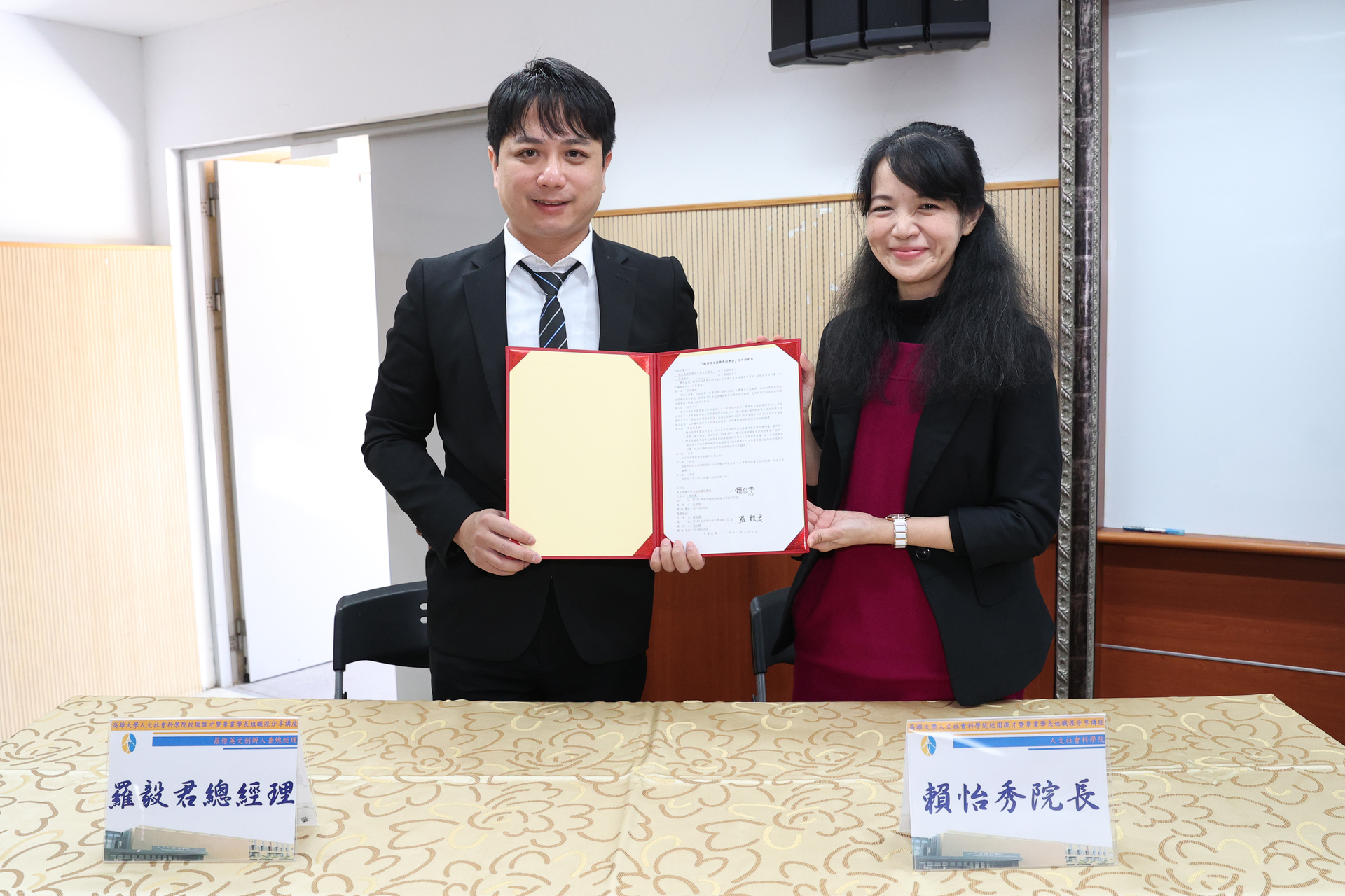 高雄大學人社院院長賴怡秀（右）、校友羅毅君代表雙方簽署捐助合約。