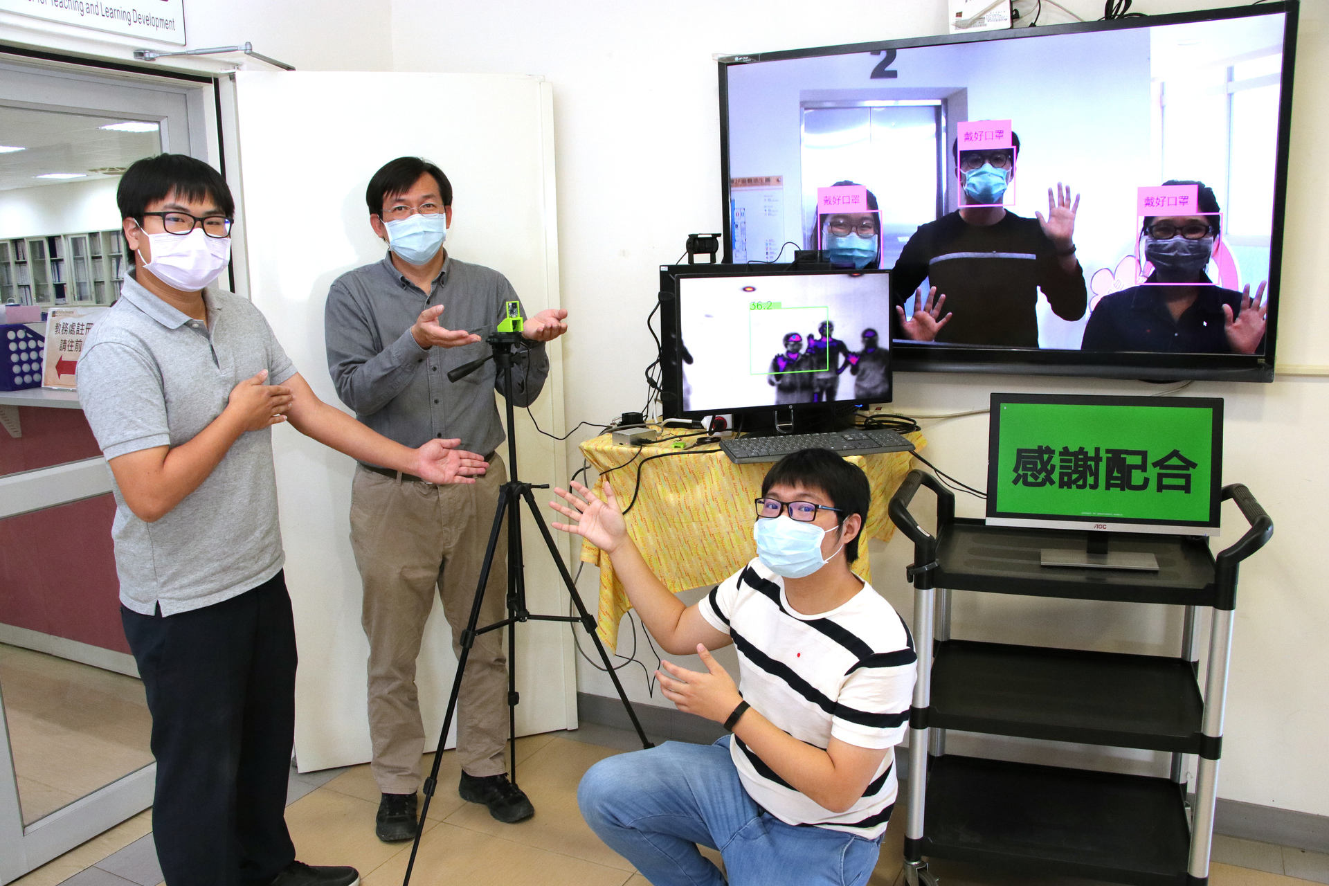 資訊管理學系副教授蕭漢威（灰襯衫），帶領碩士生羅秋馨、張廷瑋（淺灰POLO衫）、蔡家進（條紋T-Shirt）自主開發「戴口罩辨識」、「熱成像體溫量測」兩項系統。