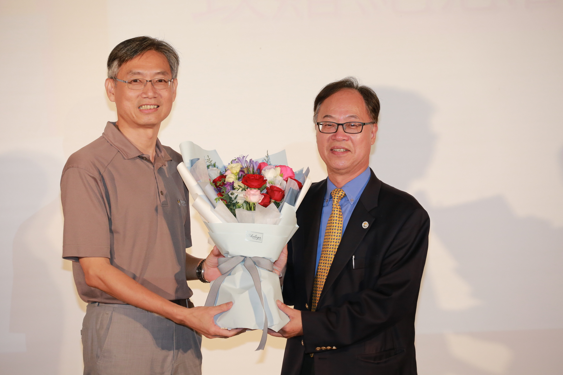 校長王學亮（右）接受行政副校長連興隆獻花致意