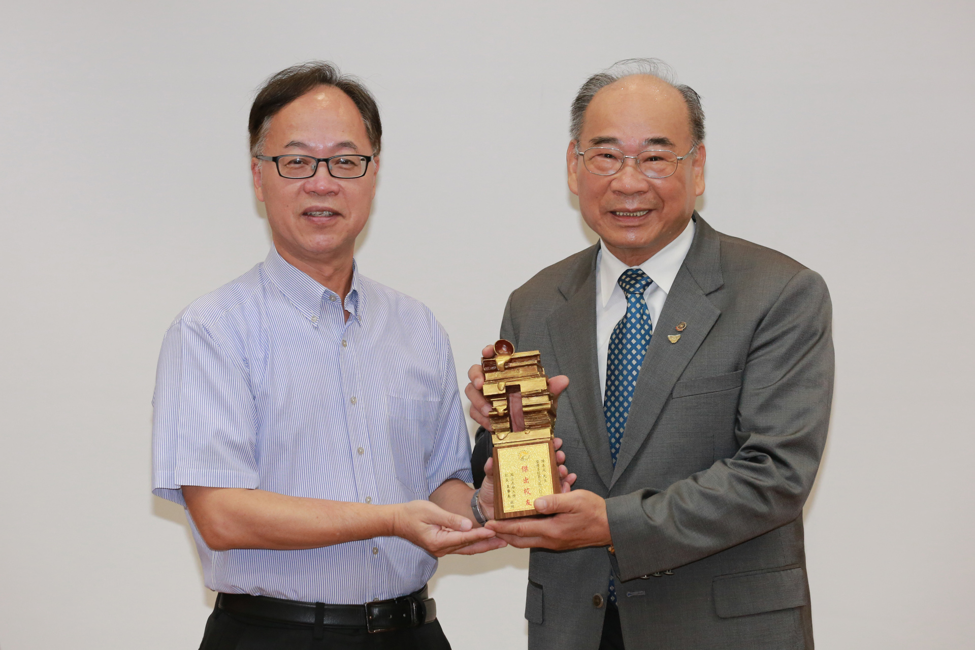 校務會議由校長王學亮（左）頒發「第3屆傑出校友」榮銜予EMBA校友陳義成。