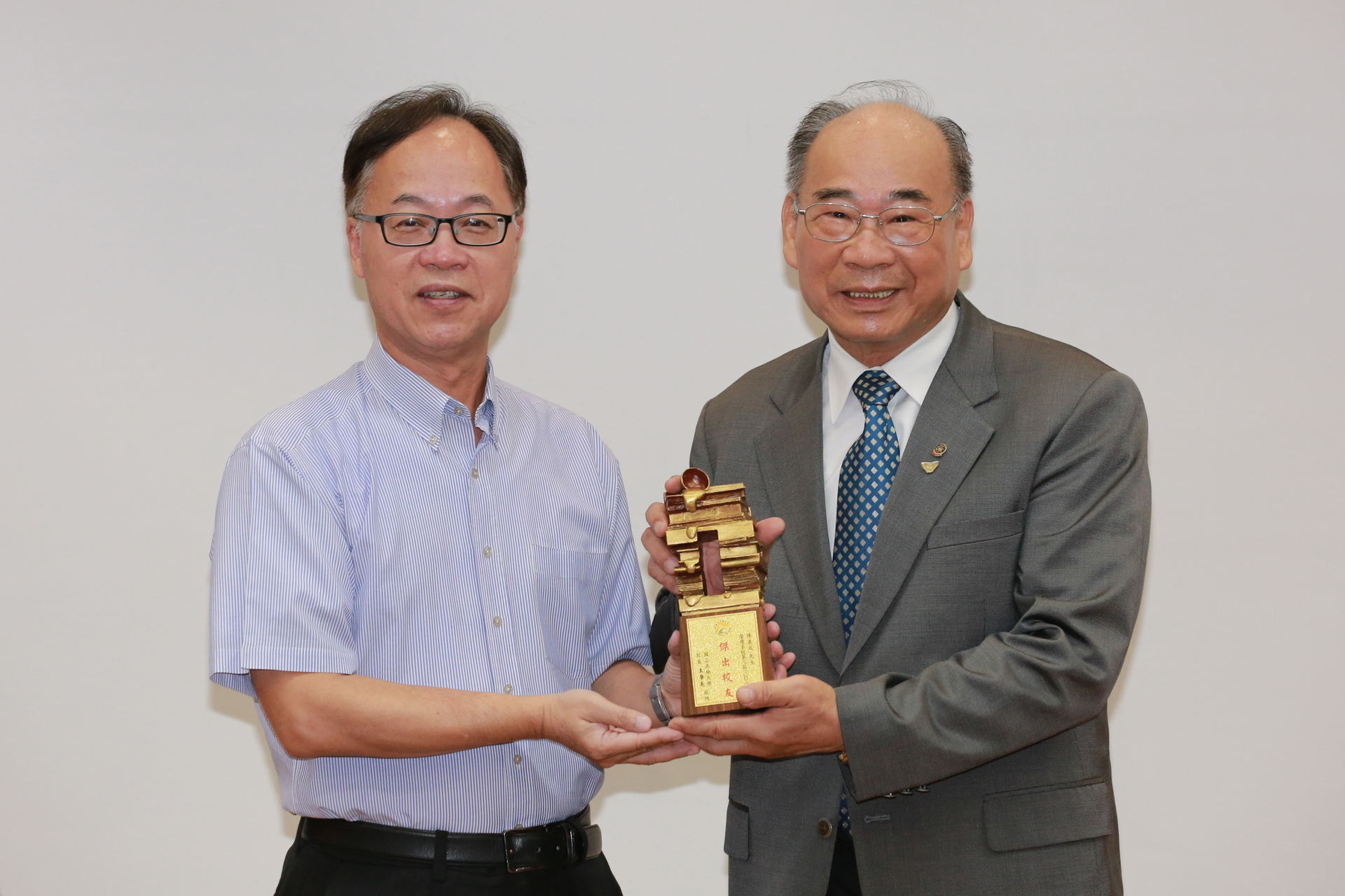 校務會議由校長王學亮（左）頒發「第3屆傑出校友」榮銜予EMBA校友陳義成。圖片