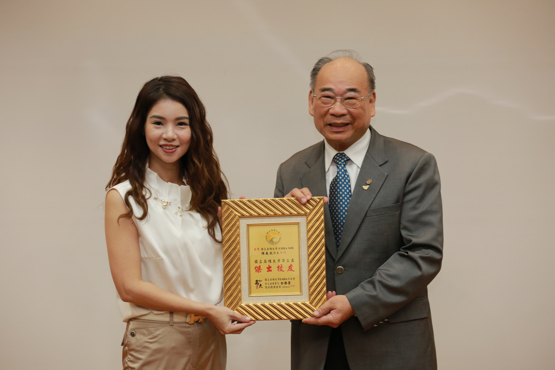高雄大學EMBA系友會理事長余靜芳（左）表揚傑出系友陳義成。圖片