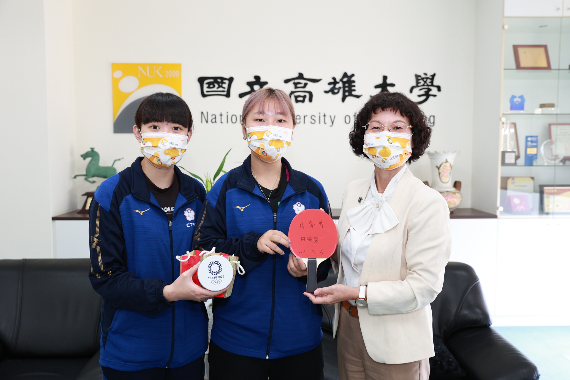 帕運桌球選手、運動競技學系學生田曉雯（左）、林姿妤回贈校長陳月端簽名球拍
