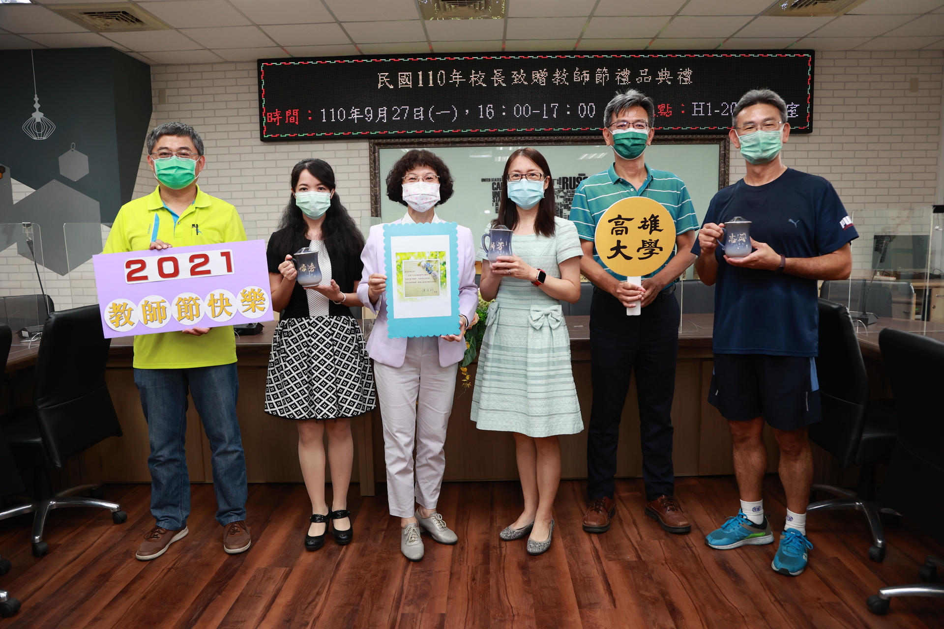 國立高雄大學校長陳月端（紫色外套）27日拜訪校內各學院、通識教育中心師長，贈以客製化「窯燒陶杯」。圖片